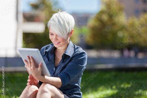Photo: Businesswoman outside in a park with tablet pc Businesswoman outside in a park with tablet pc