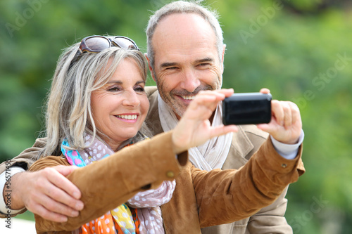Photo: Cheerful senior couple taking picture with smartphone Cheerful senior couple taking picture with smartphone