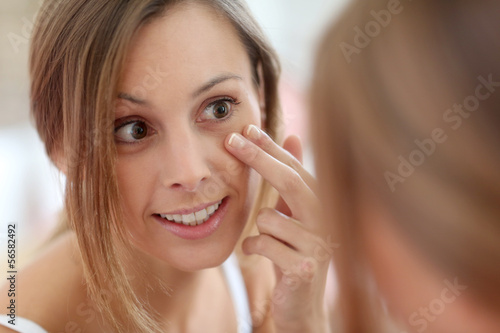 Photo: Attractive girl putting anti-aging cream on her face Attractive girl putting anti-aging cream on her face