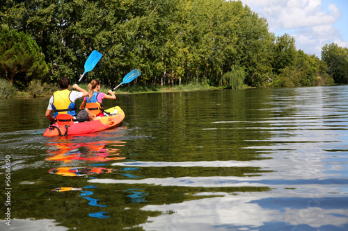 Photo: Couple riding canoe in river Couple riding canoe in river