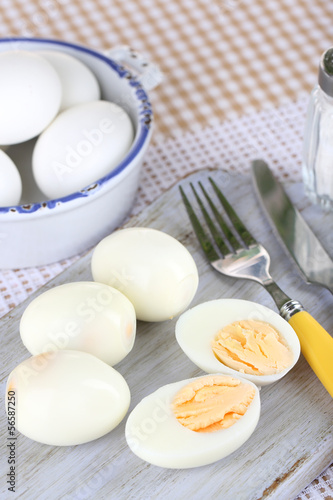 Photo: Boiled eggs on wooden board on tablecloth Boiled eggs on wooden board on tablecloth