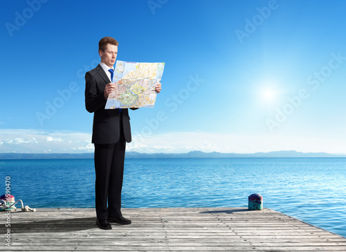 Photo: Business man standing on pier with map in hands Business man standing on pier with map in hands