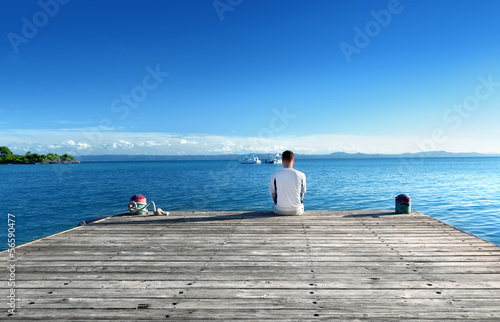 Photo: young man relax siting on pier young man relax siting on pier