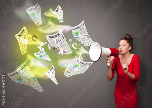 Photo: Girl yelling into loudspeaker and newspapers fly out Girl yelling into loudspeaker and newspapers fly out
