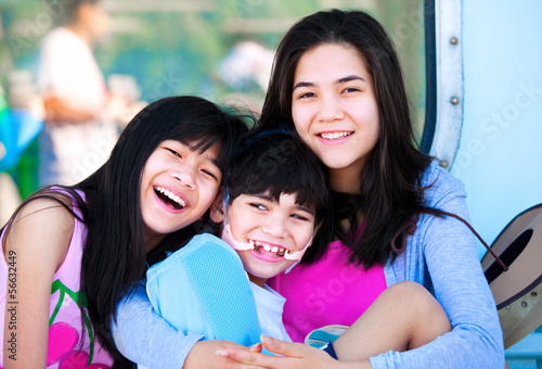 Photo: Two sisters taking care of disabled little brother Two sisters taking care of disabled little brother
