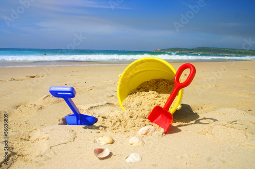Photo: Child's beach bucket and spade on a sandy beach with seashells Child's beach bucket and spade on a sandy beach with seashells
