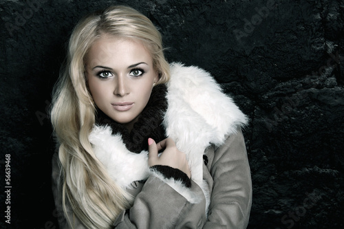 Photo: Beautiful blond woman in a fur near bricks wall.winter style Beautiful blond woman in a fur near bricks wall.winter style