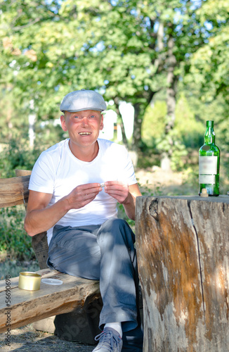 Photo: Happy man smoking and drinking in woodland Happy man smoking and drinking in woodland
