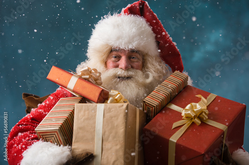 Photo: Photo of happy Santa Claus outdoors in snowfall carrying gifts t Photo of happy Santa Claus outdoors in snowfall carrying gifts t