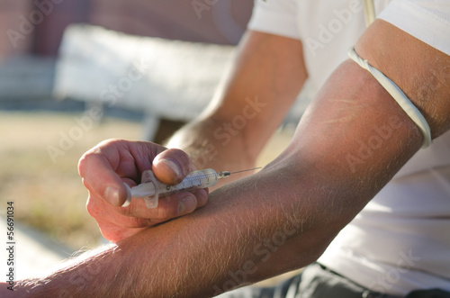 Photo: Hands of a man injecting a drug dose intravenously Hands of a man injecting a drug dose intravenously