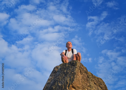 Photo: Man sitting on top of a rocky pinnacle Man sitting on top of a rocky pinnacle