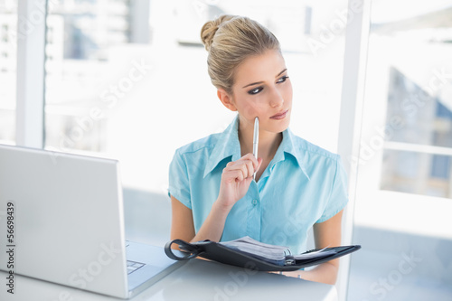 Photo: Thoughtful well dressed businesswoman writing on datebook Thoughtful well dressed businesswoman writing on datebook