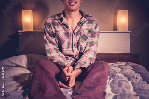 Photo: Man sitting on bed in hotel room at night Man sitting on bed in hotel room at night