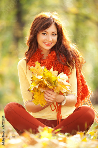 Photo: Young pretty woman relaxing in the autumn park Young pretty woman relaxing in the autumn park