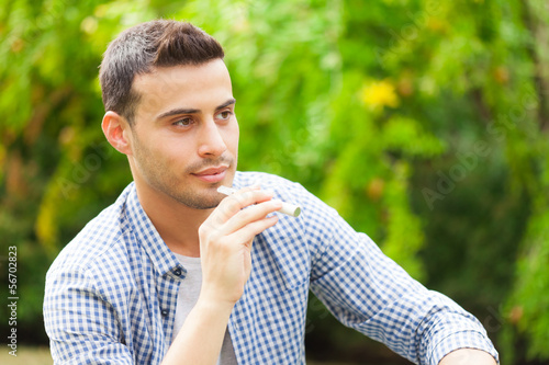 Photo: Man smoking an electronic cigarette in a park Man smoking an electronic cigarette in a park