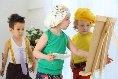 Photo: Small children draw pictures on an easel Small children draw pictures on an easel