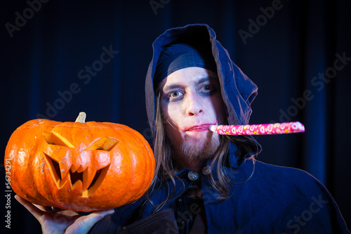 Photo: Man in scary Halloween costume holding pumpkin Man in scary Halloween costume holding pumpkin