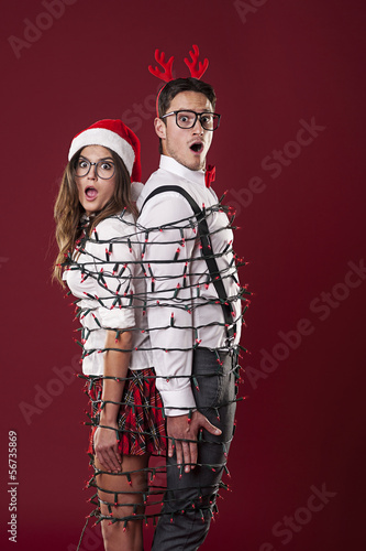 Photo: Funny nerd couple are tangling in christmas lights Funny nerd couple are tangling in christmas lights