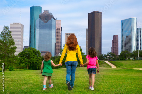 Photo: Mother and daughters walking holding hands on city skyline Mother and daughters walking holding hands on city skyline