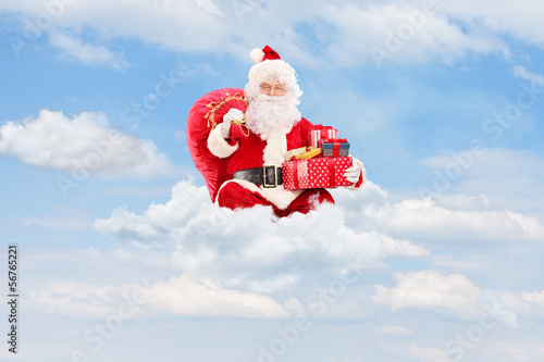 Photo: Santa Claus holding a bag full of presents on clouds Santa Claus holding a bag full of presents on clouds
