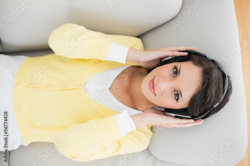 Photo: Smiling casual brunette in yellow cardigan listening to music wi Smiling casual brunette in yellow cardigan listening to music wi