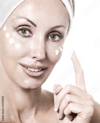 Photo: The beautiful young woman in towel with a cosmetic cream.. The beautiful young woman in towel with a cosmetic cream..