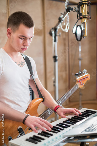 Photo: Musician with a guitar around his neck plays keyboards Musician with a guitar around his neck plays keyboards