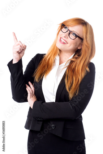 Photo: Smiling businesswoman pointing upwards Smiling businesswoman pointing upwards
