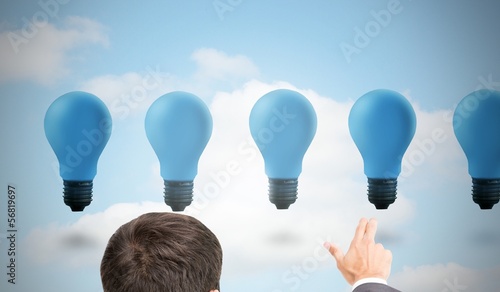 Photo: Businessman pointing with two fingers at blue light bulbs Businessman pointing with two fingers at blue light bulbs