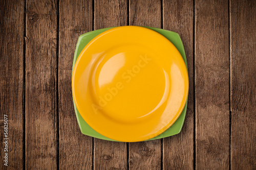 Photo: Colorful empty plate on grungy background table Colorful empty plate on grungy background table