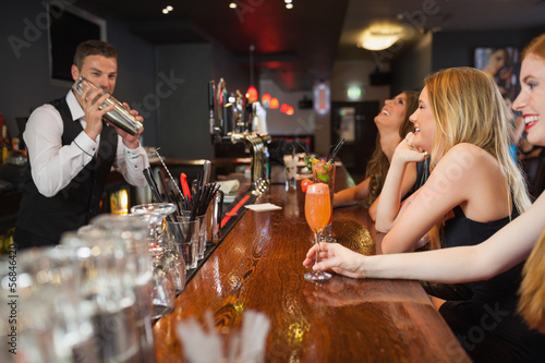 Photo: Handsome bartender making cocktails for beautiful women Handsome bartender making cocktails for beautiful women