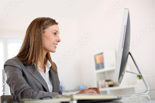 Photo: Saleswoman in office working on desktop computer Saleswoman in office working on desktop computer