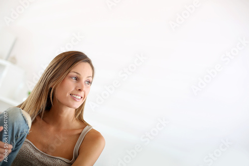 Photo: Beautiful young woman sitting in couch at home Beautiful young woman sitting in couch at home