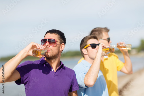 Photo: friends on the beach with bottles of drink friends on the beach with bottles of drink