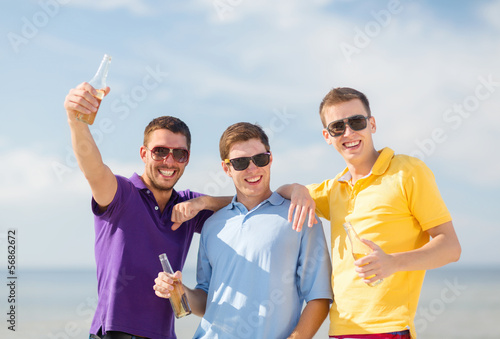 Photo: friends on the beach with bottles of drink friends on the beach with bottles of drink