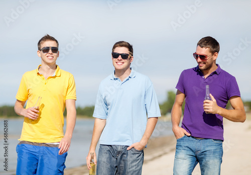 Photo: friends on the beach with bottles of drink friends on the beach with bottles of drink