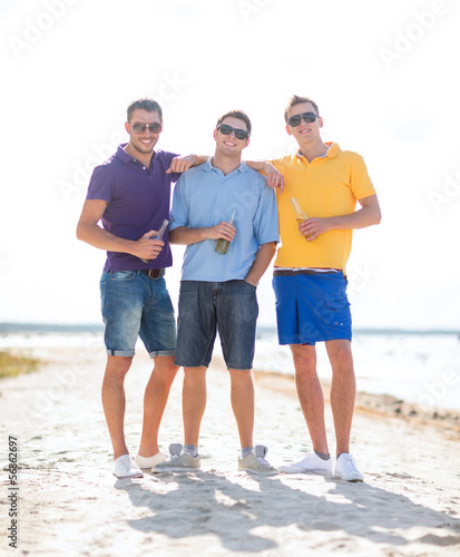 Photo: friends on the beach with bottles of drink friends on the beach with bottles of drink
