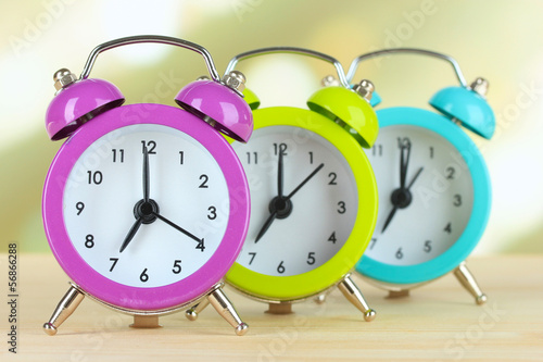Photo: Colorful alarm clocks on table on light background Colorful alarm clocks on table on light background