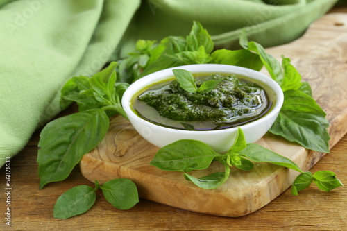 Photo: pesto sauce with basil and olive oil on a wooden table pesto sauce with basil and olive oil on a wooden table