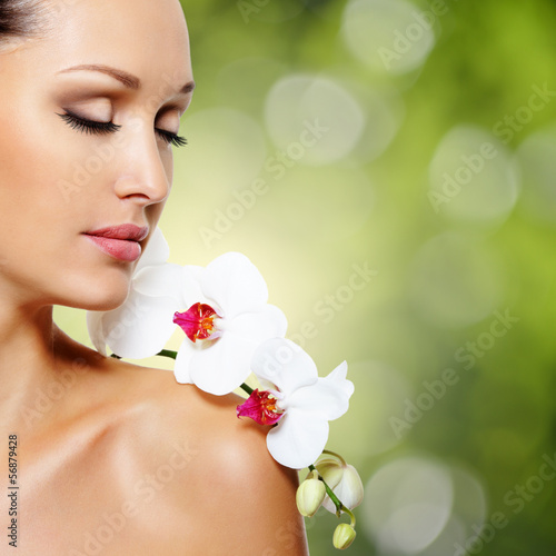 Photo: Face of beautiful woman with a white orchid flower Face of beautiful woman with a white orchid flower