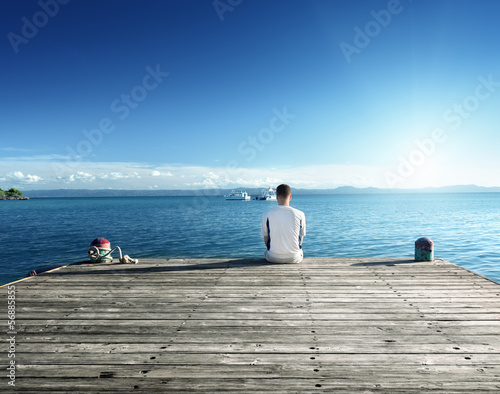 Photo: young man relax siting on pier young man relax siting on pier