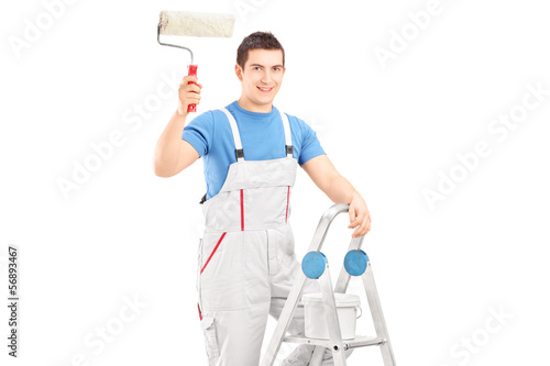 Photo: Male painter holding a roller and standing on a ladder Male painter holding a roller and standing on a ladder