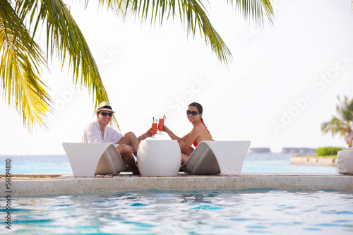 Photo: happy young couple relax and take fresh drink on poolside happy young couple relax and take fresh drink on poolside