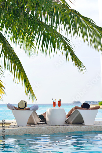 Photo: happy young couple relax and take fresh drink on poolside happy young couple relax and take fresh drink on poolside