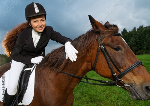 Photo: Beautiful smiling girl sitting on a horse outdoors Beautiful smiling girl sitting on a horse outdoors