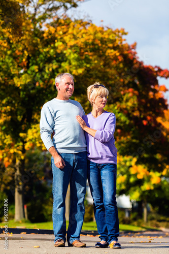 Photo: Seniors in autumn or fall walking hand in hand Seniors in autumn or fall walking hand in hand