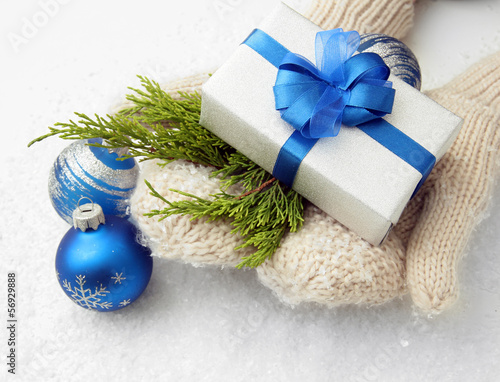 Photo: Female hands in mittens with gift box, on white background Female hands in mittens with gift box, on white background