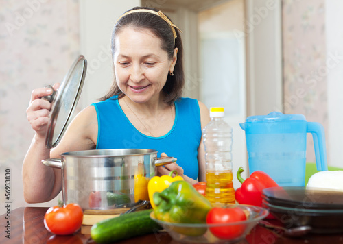 Photo: mature woman cooking with vegetables mature woman cooking with vegetables