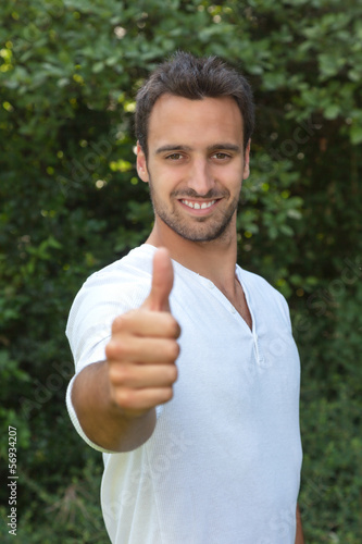 Photo: Latin man showing thumb in a park Latin man showing thumb in a park