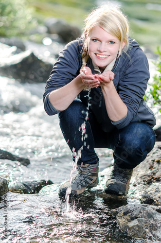 Photo: junge blonde Frau beim Wandern erfrischt sich am einem Bach junge blonde Frau beim Wandern erfrischt sich am einem Bach